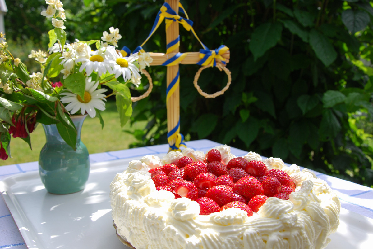 Picture of a Midsommar pole, bouquet of flowers and a strawberry cake